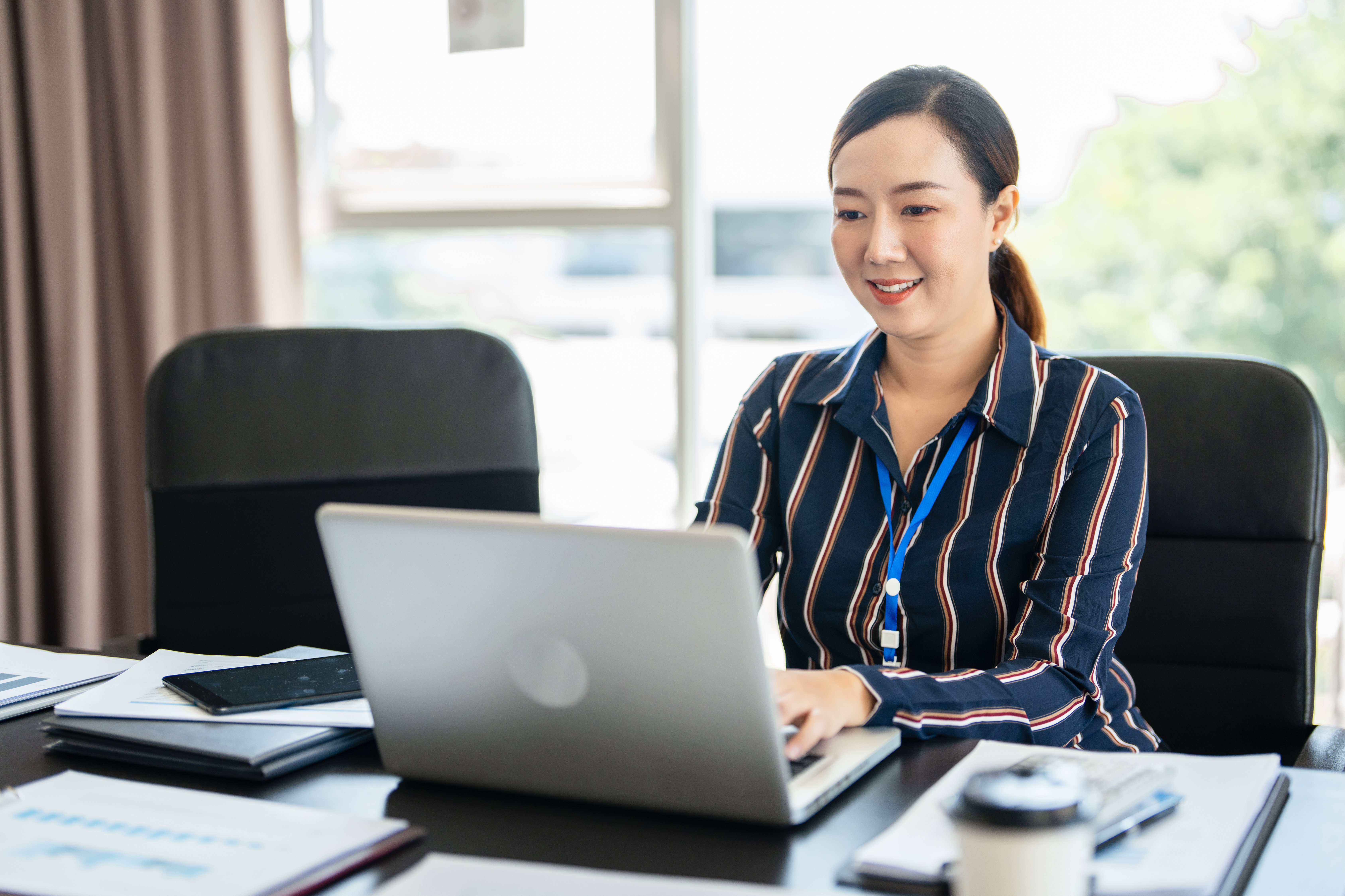 Professional woman reviewing notes at office laptop